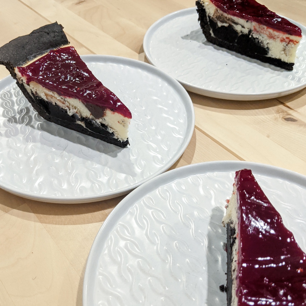 Three slices of chocolate-swirled cheesecake with chocolate crusts and raspberry topping